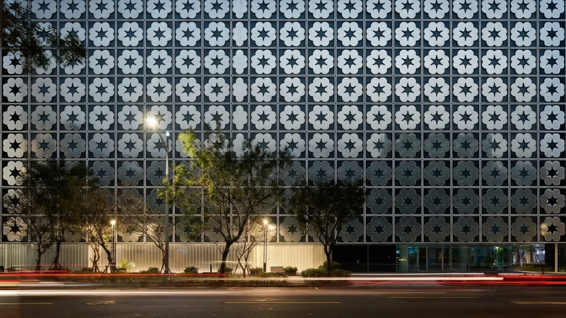 The petal screen wall glowing over the street at dusk