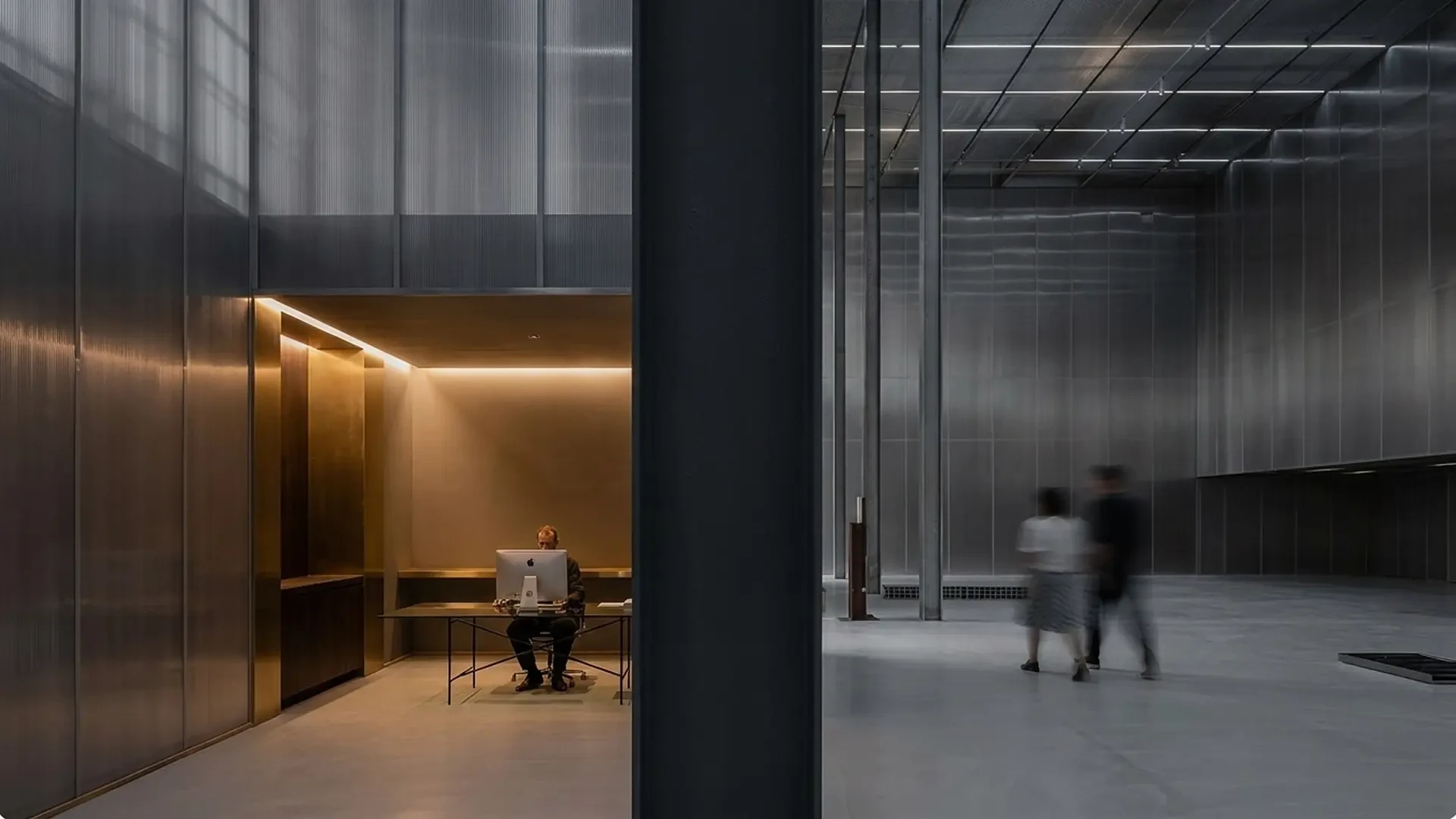 Modern interior workspace with warm lighting, desk, and people
